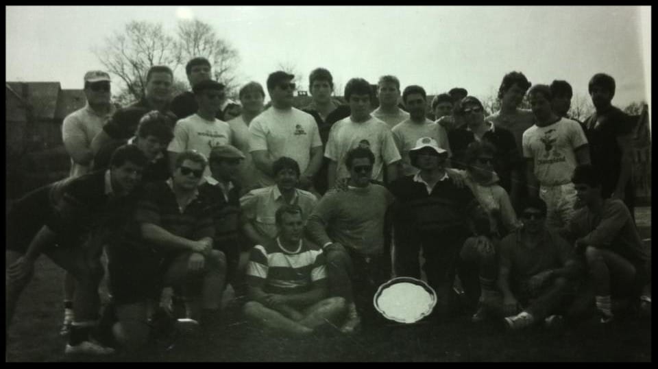 Black-and-white photo of the first Maddog team with a trophy